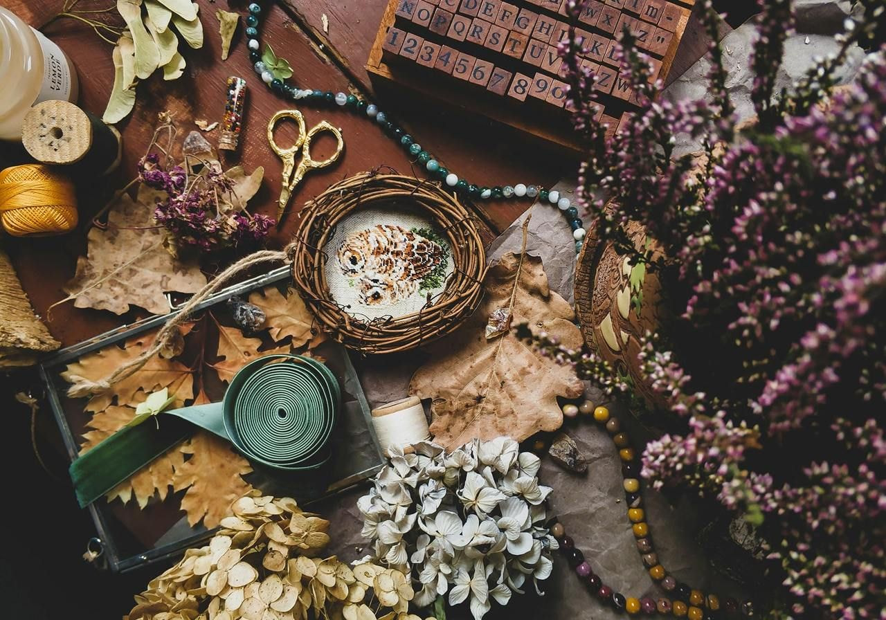 A table displaying a candle, scissors, and a bowl filled with dried flowers, creating a cozy and artistic arrangement.